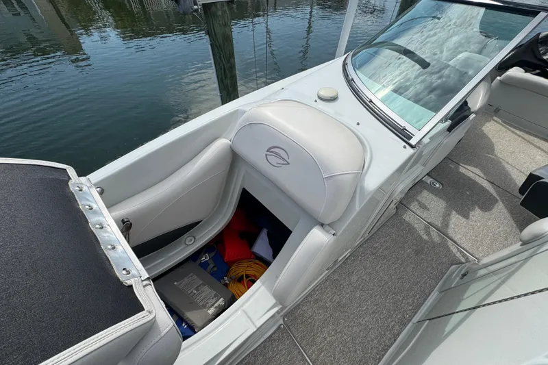 Slide: The Image of 2015 Crownline 285 SS boat interior with storage compartment open, docked by water. - 14