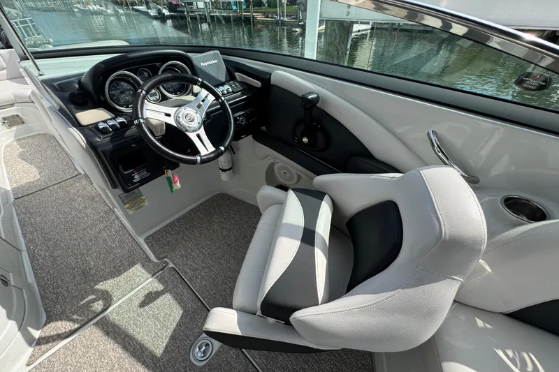 Slide: The Image of 2015 Crownline 285 SS boat cockpit with steering wheel and controls, docked by the water. - 35
