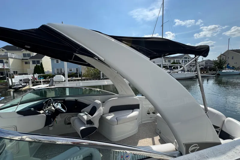 Slide: The Image of 2015 Crownline 285 SS boat with canopy, docked in a marina under a clear sky. - 52