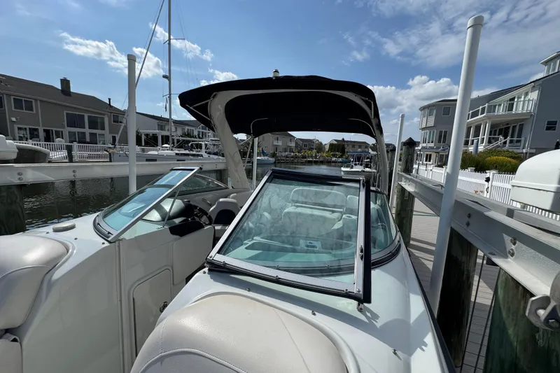 Slide: The Image of 2015 Crownline 285 SS boat docked at a marina with waterfront homes. - 55