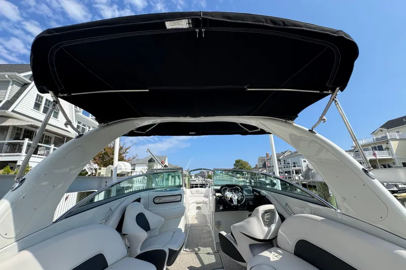 Slide: The Image of 2015 Crownline 285 SS boat interior with canopy, docked near waterfront homes. - 68