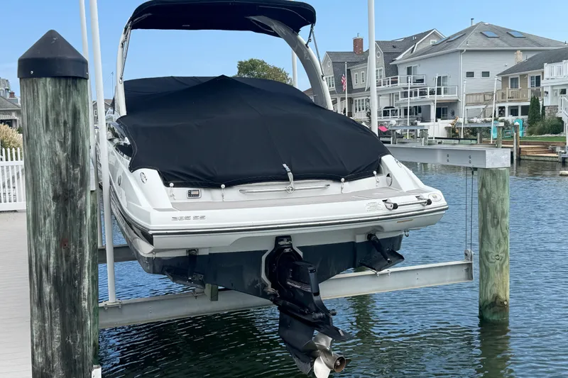 Slide: The Image of 2015 Crownline 285 SS boat on lift, covered, docked near waterfront homes. - 8