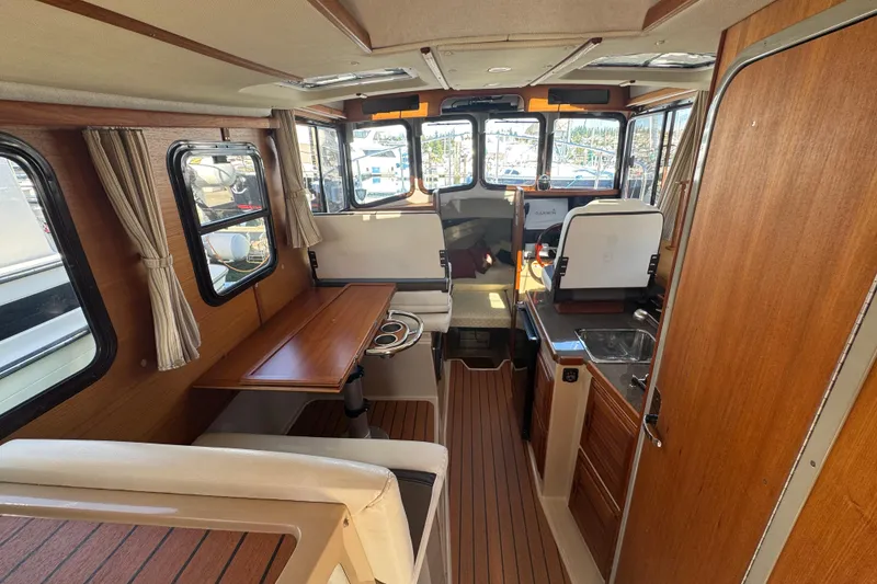 Slide: The Image of 2016 Ranger Tugs R-25SC interior with wood finish, dining area, and helm station. - 12