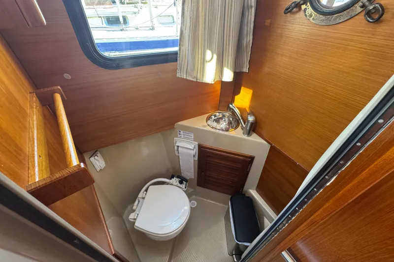 Slide: The Image of 2016 Ranger Tugs R-25SC boat bathroom with wooden interior and compact design. - 14