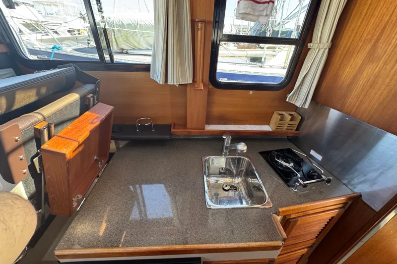 Slide: The Image of 2016 Ranger Tugs R-25SC interior kitchen with sink, stove, and wooden cabinetry. - 8