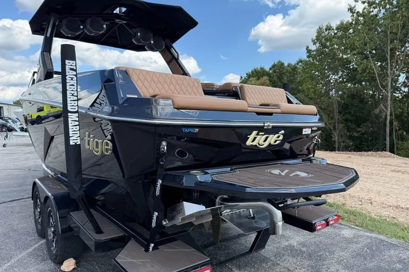 Slide: The Image of 2026 Tigé Z3 boat with sleek design, parked on a trailer, under a partly cloudy sky. - 6