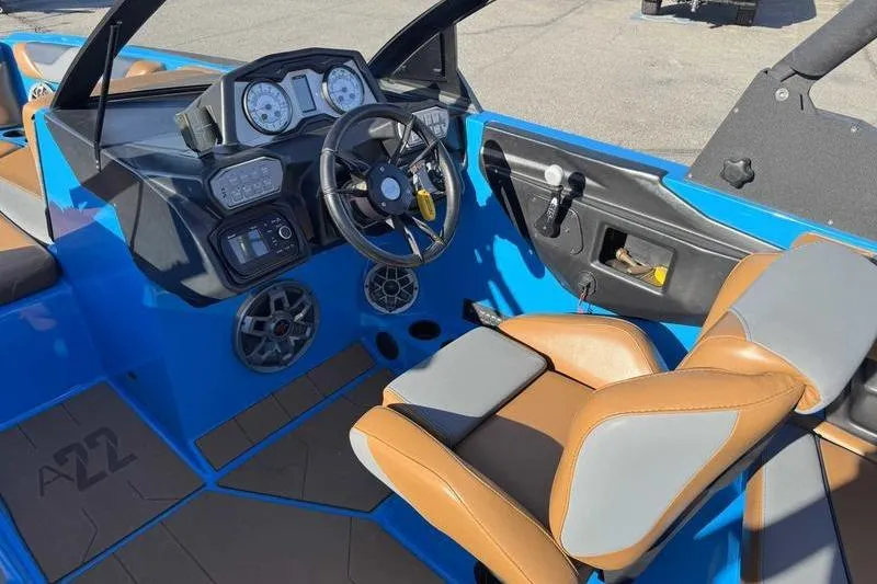 Slide: The Image of 2021 Axis A22 boat interior with blue and brown seating, steering wheel, and dashboard controls. - 10