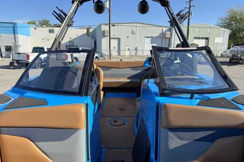 Slide: The Image of 2021 Axis A22 boat interior with blue and brown seating, parked outdoors. - 11
