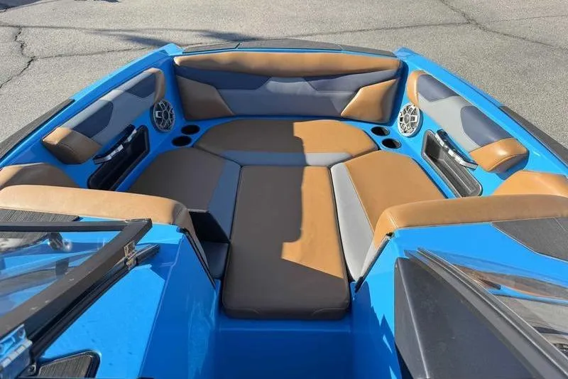 Slide: The Image of 2021 Axis A22 boat interior with blue and brown seating, cup holders, and speakers. - 13