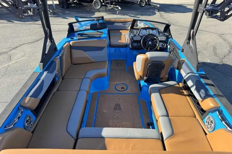 Slide: The Image of 2021 Axis A22 boat interior with tan and blue seating, modern dashboard, and spacious layout. - 2