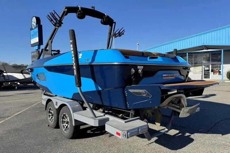 Slide: The Image of 2021 Axis A22 boat on trailer, blue exterior, parked outside dealership. - 6