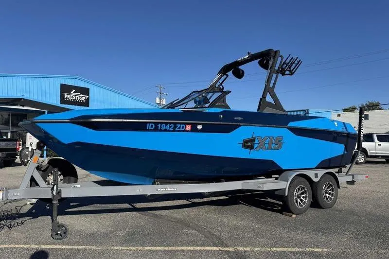 Slide: The Image of 2021 Axis A22 blue boat on trailer at dealership, sunny day. - 8