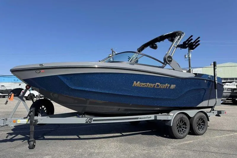 Slide: The Image of 2026 MasterCraft XT22 boat on trailer, blue exterior, parked outdoors. - 2