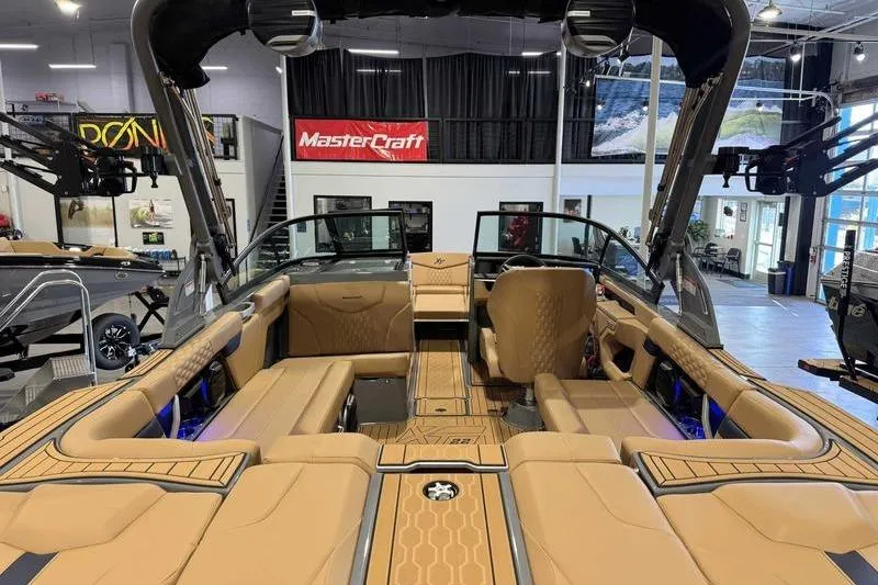 Slide: The Image of 2026 MasterCraft XT22 boat interior with tan seating and modern design in showroom. - 8
