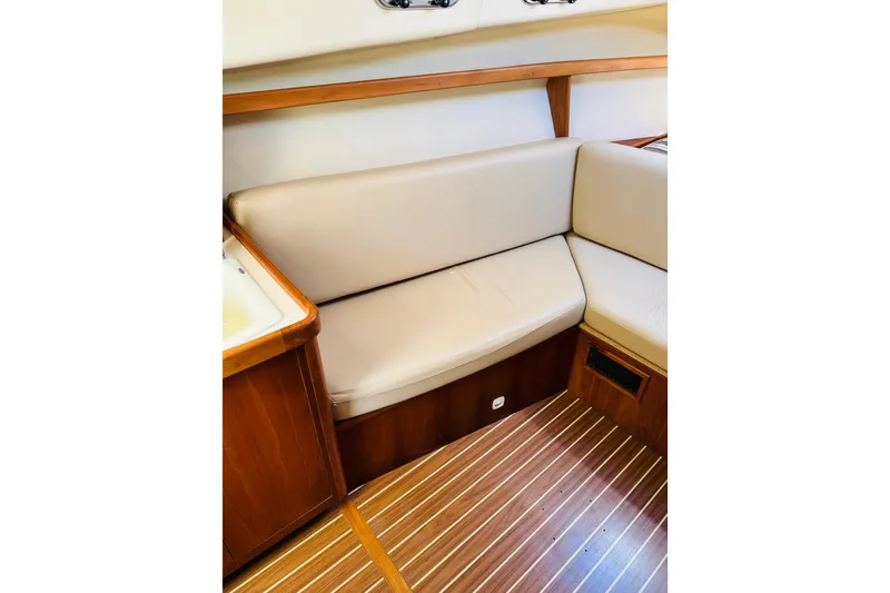 Slide: The Image of 2006 Mainship Pilot 30 Sedan interior with beige seating and wooden flooring. - 4
