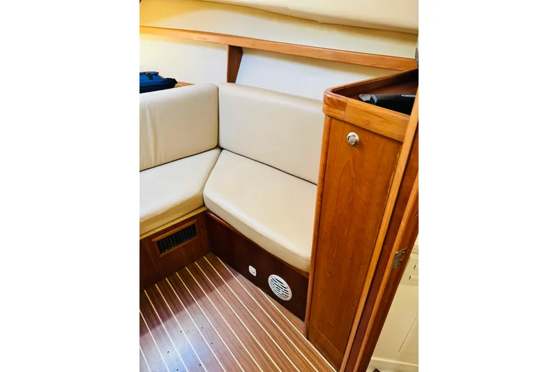 Slide: The Image of 2006 Mainship Pilot 30 Sedan interior with beige seating and wooden cabinetry. - 5