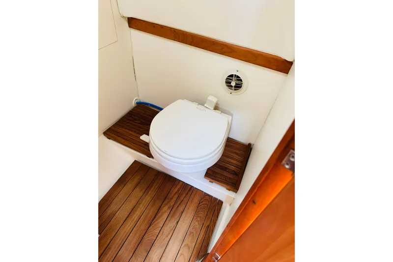 Slide: The Image of 2006 Mainship Pilot 30 Sedan boat bathroom with wooden flooring and compact toilet. - 7