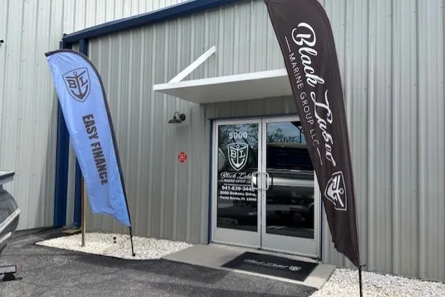 Slide: The Image of Exterior of Black Label Marine Group dealership with flags, featuring Caymas 26 HB, 2023 model. - 6