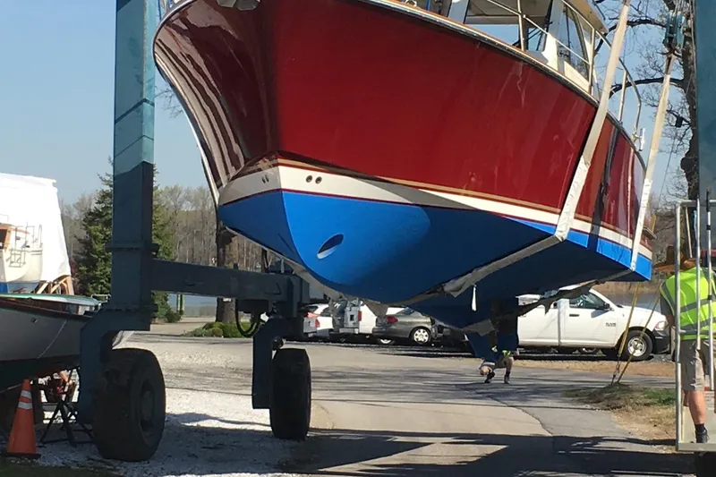 Slide: The Image of 2007 Legacy Yachts 32 being transported on a boat lift, showcasing red and blue hull. - 15