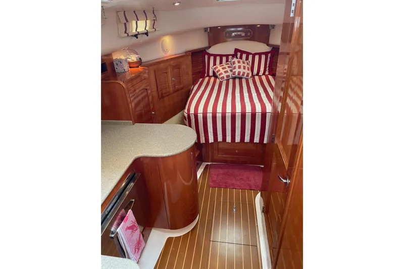 Slide: The Image of Luxurious 2007 Legacy Yachts 32 interior with striped bedding and polished wood finishes. - 21