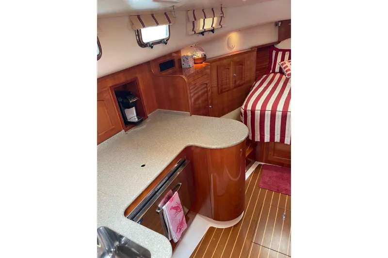 Slide: The Image of Interior of 2007 Legacy Yachts 32, featuring a cozy kitchen and striped bedding. - 22