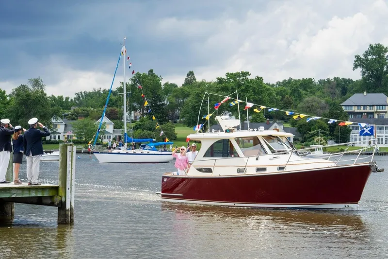 Slide: The Image of 2007 Legacy Yachts 32 cruising on a scenic river, decorated with colorful flags. - 3
