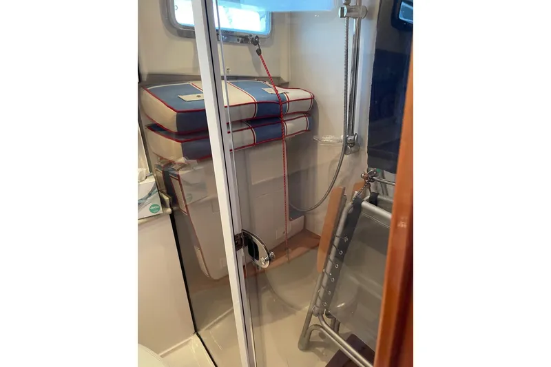 Slide: The Image of Interior of 2007 Legacy Yachts 32, featuring a compact shower area with nautical cushions. - 32