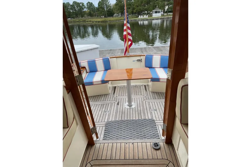 Slide: The Image of 2007 Legacy Yachts 32 interior with striped seating and wooden table, overlooking serene water. - 33