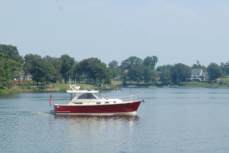 Slide: The Image of 2007 Legacy Yachts 32 cruising on a serene lake with lush green shoreline. - 4