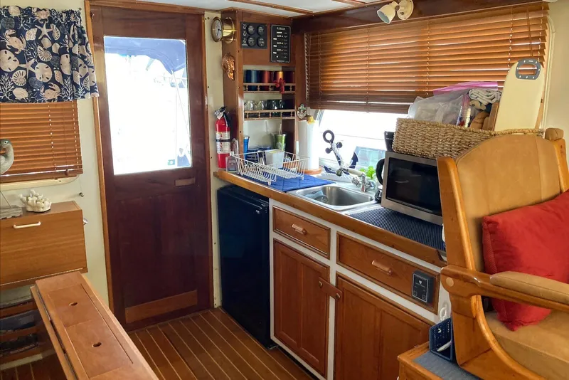 Slide: The Image of Cozy 1993 Flye Point 31 boat kitchen with wooden cabinets, sink, and microwave. - 9