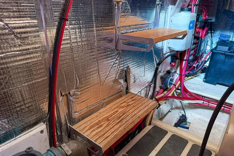 Slide: The Image of Engine room of a 1999 Nordic Tug 37 with shelves and wiring. - 38