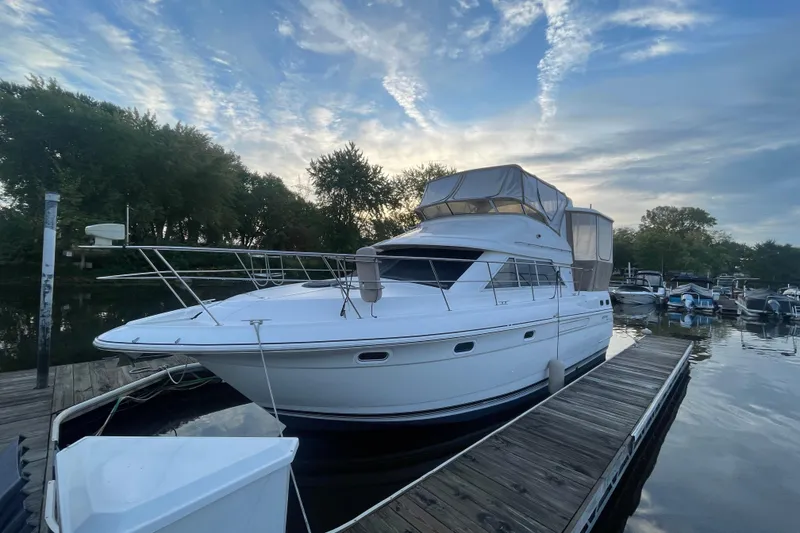 Slide: The Image of 1997 Cruisers Yachts 3650 Aft Cabin docked, serene water, and cloudy sky backdrop. - 5