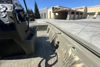 Slide: The Image of 2019 Tracker Grizzly 1860 CC boat interior near a warehouse. - 3