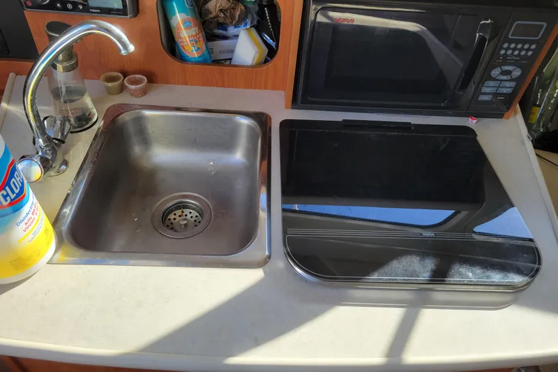 Slide: The Image of 2003 Bayliner 245 boat kitchen with sink, stove, and microwave. - 23