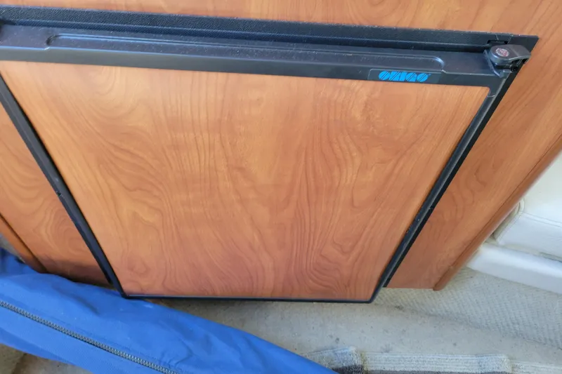 Slide: The Image of 2003 Bayliner 245 boat interior with wooden panel and blue fabric cover. - 24