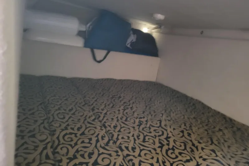 Slide: The Image of 2003 Bayliner 245 cabin interior with patterned bedding and storage items. - 31