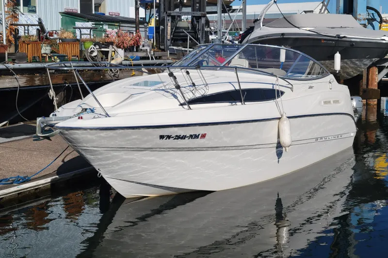 Slide: The Image of 2003 Bayliner 245 boat docked at marina, reflecting on water. - 4