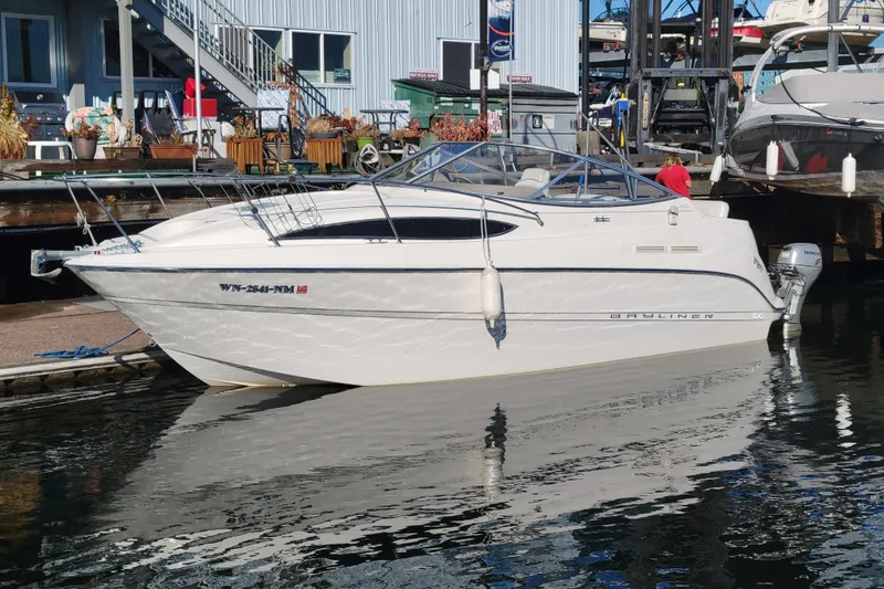 Slide: The Image of 2003 Bayliner 245 boat docked at marina, reflecting on calm water. - 5