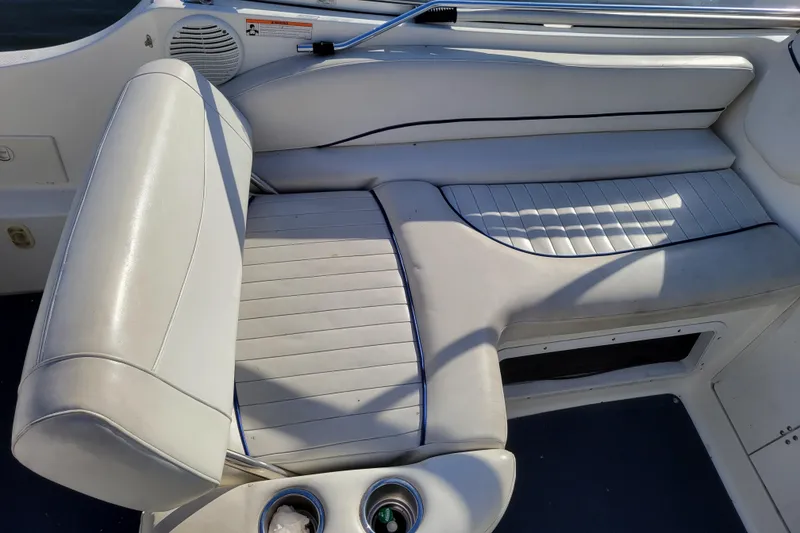 Slide: The Image of 2003 Bayliner 245 boat interior with white cushioned seating and cup holders. - 8