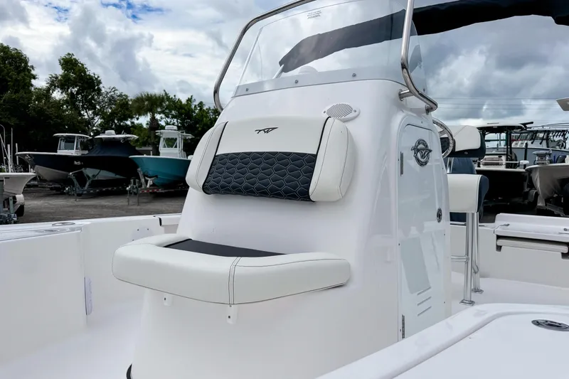 Slide: The Image of 2026 Tidewater 2110 Bay Max boat interior with cushioned seating and console, under cloudy sky. - 12