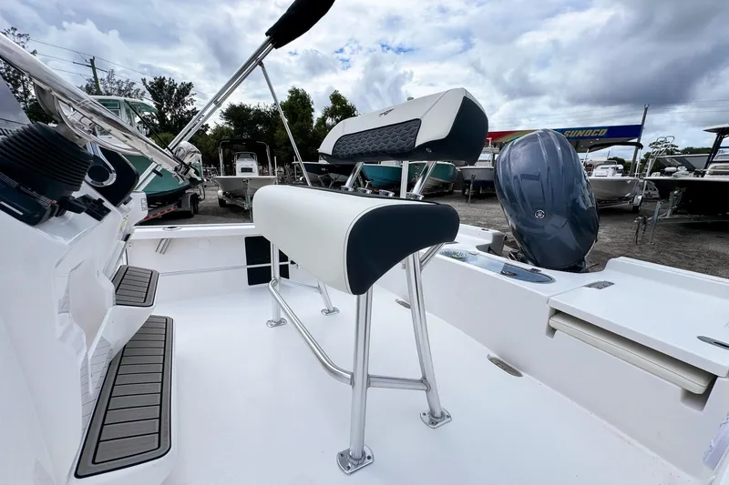 Slide: The Image of 2026 Tidewater 2110 Bay Max boat interior with seating and motor, under cloudy sky. - 9
