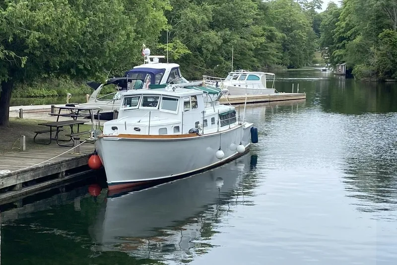 Slide: The Image of 1963 Wiley Trawler docked on a serene river, surrounded by lush greenery. - 31
