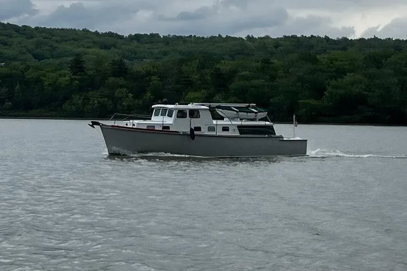 Slide: The Image of 1963 Wiley Trawler cruising on a calm lake with lush green forest backdrop. - 32