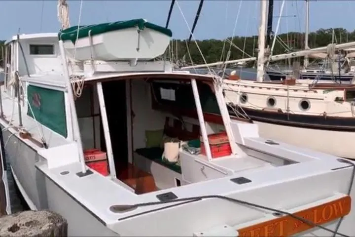 Slide: The Image of 1963 Wiley Trawler docked at a marina, surrounded by other boats and lush greenery. - 4