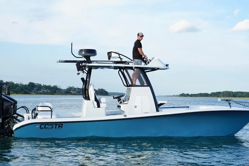 Slide: The Image of 2025 Costa Custom Boats 264 HC cruising on a scenic waterway with lush greenery. - 10