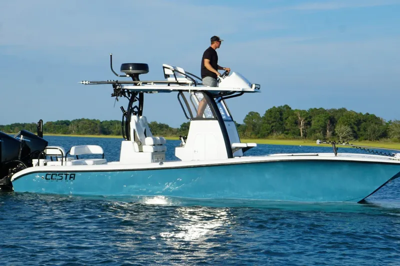 Slide: The Image of 2025 Costa Custom Boats 264 HC cruising on a river with lush green trees in the background. - 12