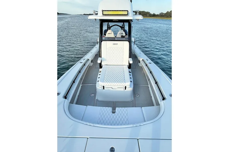 Slide: The Image of 2025 Costa Custom Boats 264 HC, sleek interior view with rod holders and storage, on calm water. - 18