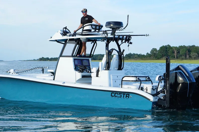 Slide: The Image of 2025 Costa Custom Boats 264 HC cruising on a river with lush greenery in the background. - 2