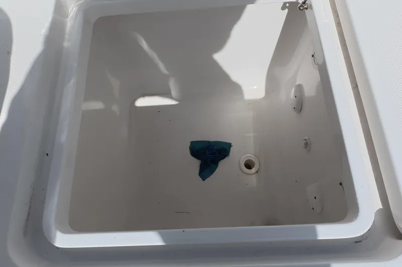 Slide: The Image of Open storage compartment on 2023 Invincible 33 Catamaran with a blue cloth inside. - 13