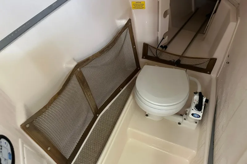 Slide: The Image of 2011 Grady-White Freedom 275 boat interior with marine toilet and storage nets. - 29